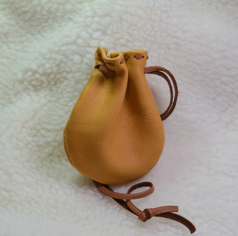 Small (approximately 3 to 4 inches), tan deerskin pouch with brown leather lace drawstring closure - closed view