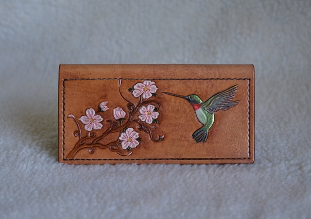 Leather checkbook cover with a carved painted hummingbird