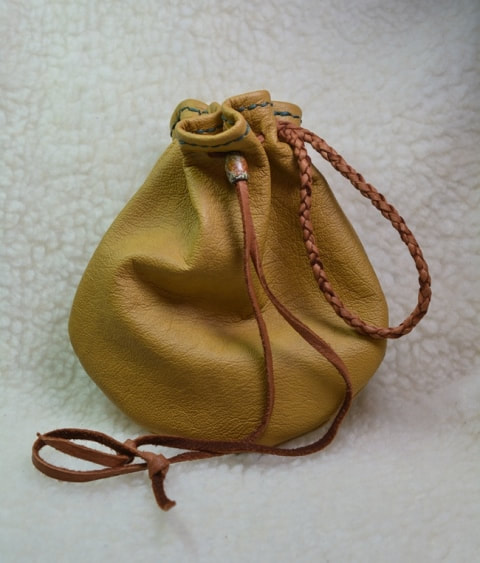 Large (approximately 5 to 6 inches) tan leather pouch with brown leather lace drawstring closure - closed view
